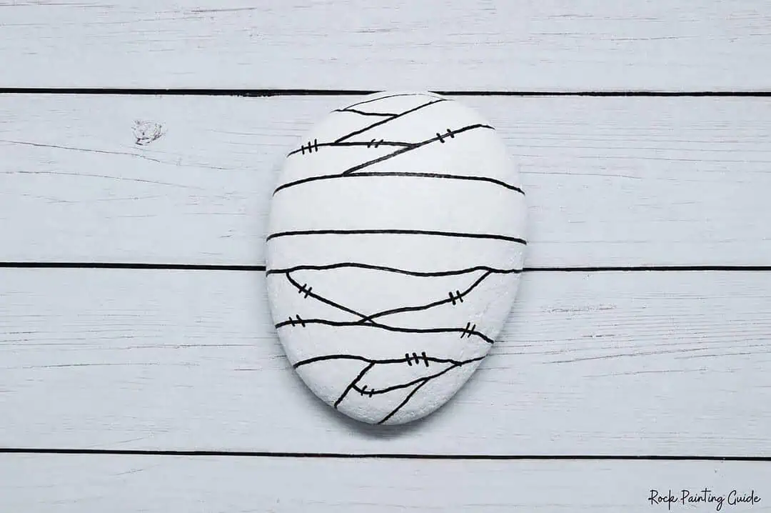 Easy Mummy Rock Painting: Step-by-Step Halloween Tutorial 6 Mummy-themed painted rock with bandage design for Halloween.