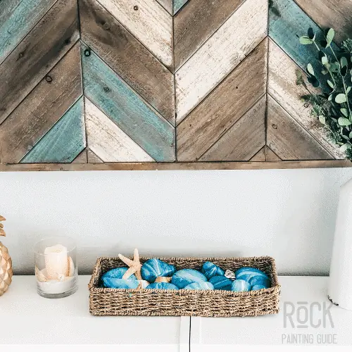 8 Easy Paint Pouring Techniques to Create Beautiful Wall Art 16 beach painted rocks in a jute basket displayed on a bookcase