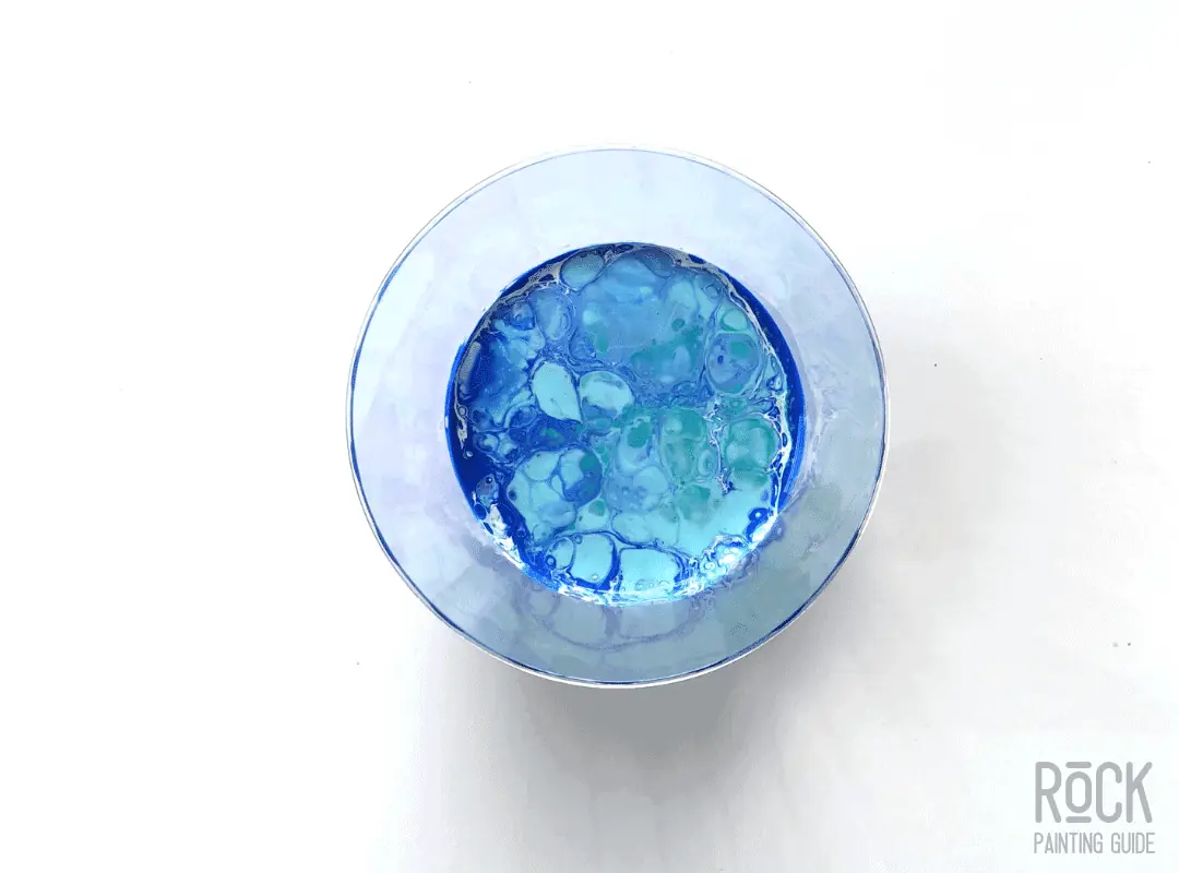 8 Easy Paint Pouring Techniques to Create Beautiful Wall Art 6 a cup of a dirty pour with blue, white, and green paint