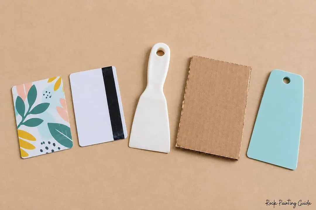 Easy Ghost Craft: Halloween Squeegee Painting for Kids 4 Alternative tools for squeegee painting including plastic cards, a paint scraper, cardboard, and a flat crafting tool
