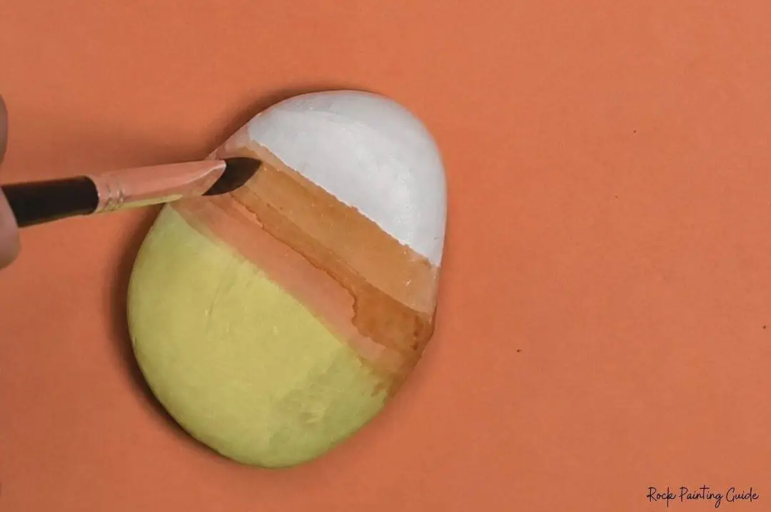 Candy Corn Painted Rocks: Easy Alcohol Ink Rock Painting Tutorial 6 Painted rock resembling a candy corn with white, orange, and yellow sections.
