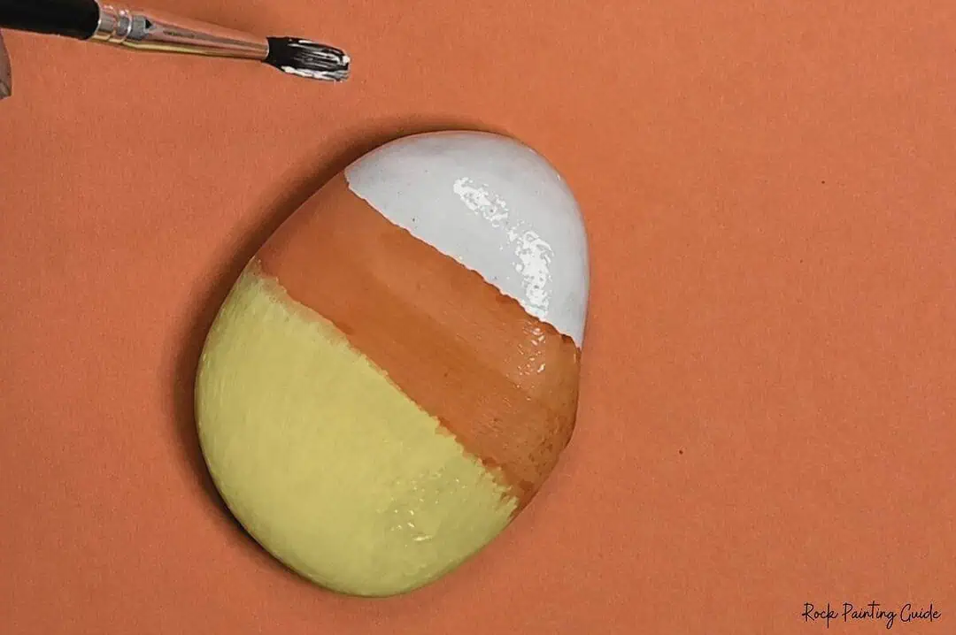 Candy Corn Painted Rocks: Easy Alcohol Ink Rock Painting Tutorial 7 Painted rock resembling a candy corn with white, orange, and yellow sections.