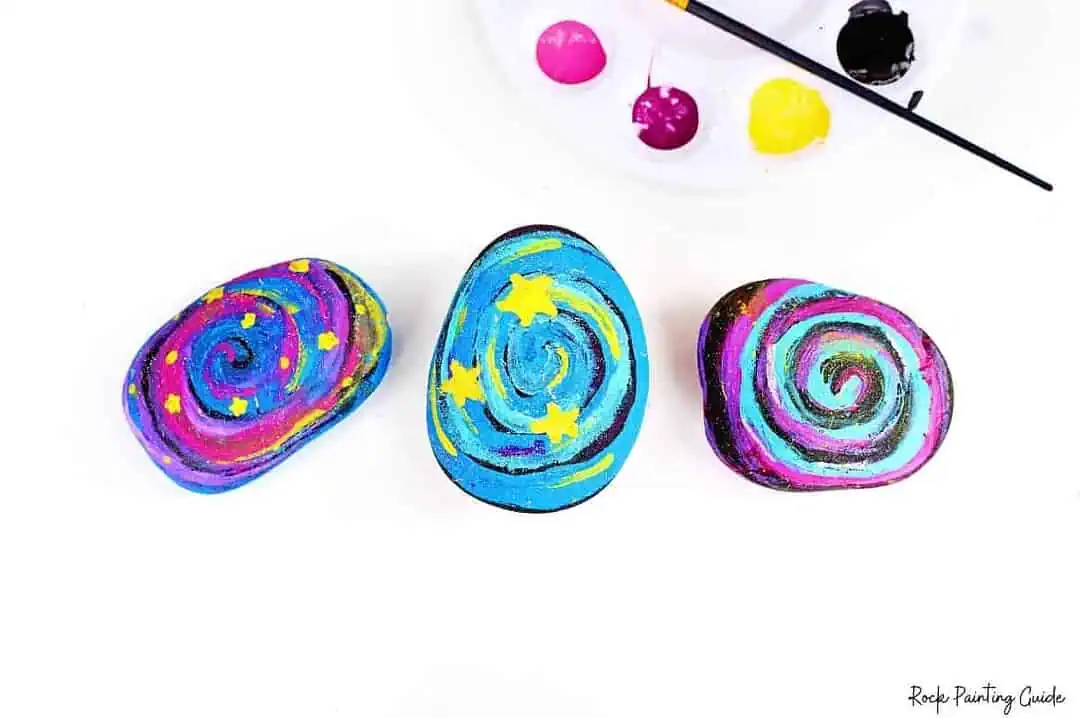 Easy Starry Night Sky Galaxy Painted Rocks for Beginners 3 Brightly painted rocks featuring galaxy and star motifs for rock painting art projects.
