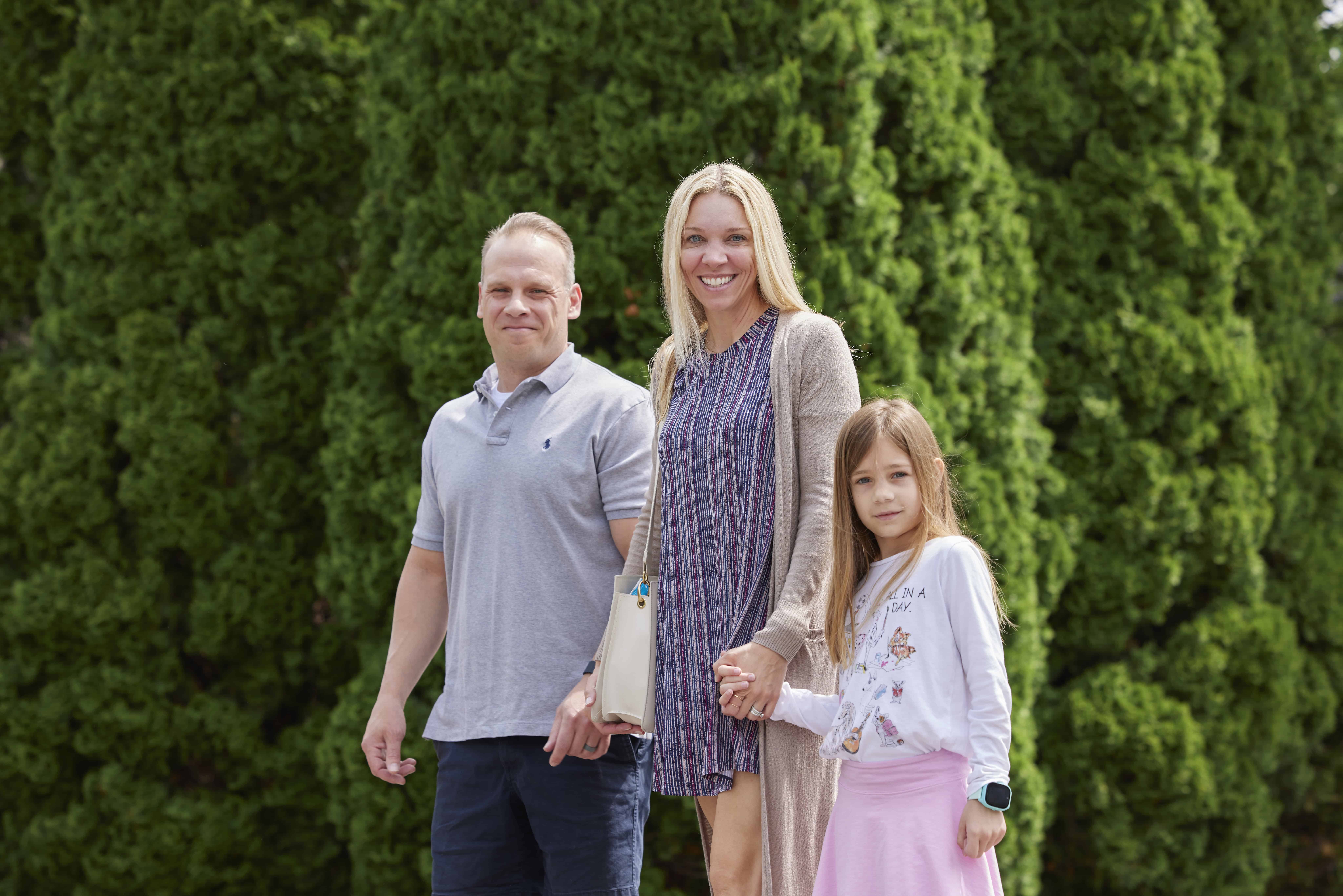 Family standing outdoors at Rolling Hills Community Church, smiling and holding hands.