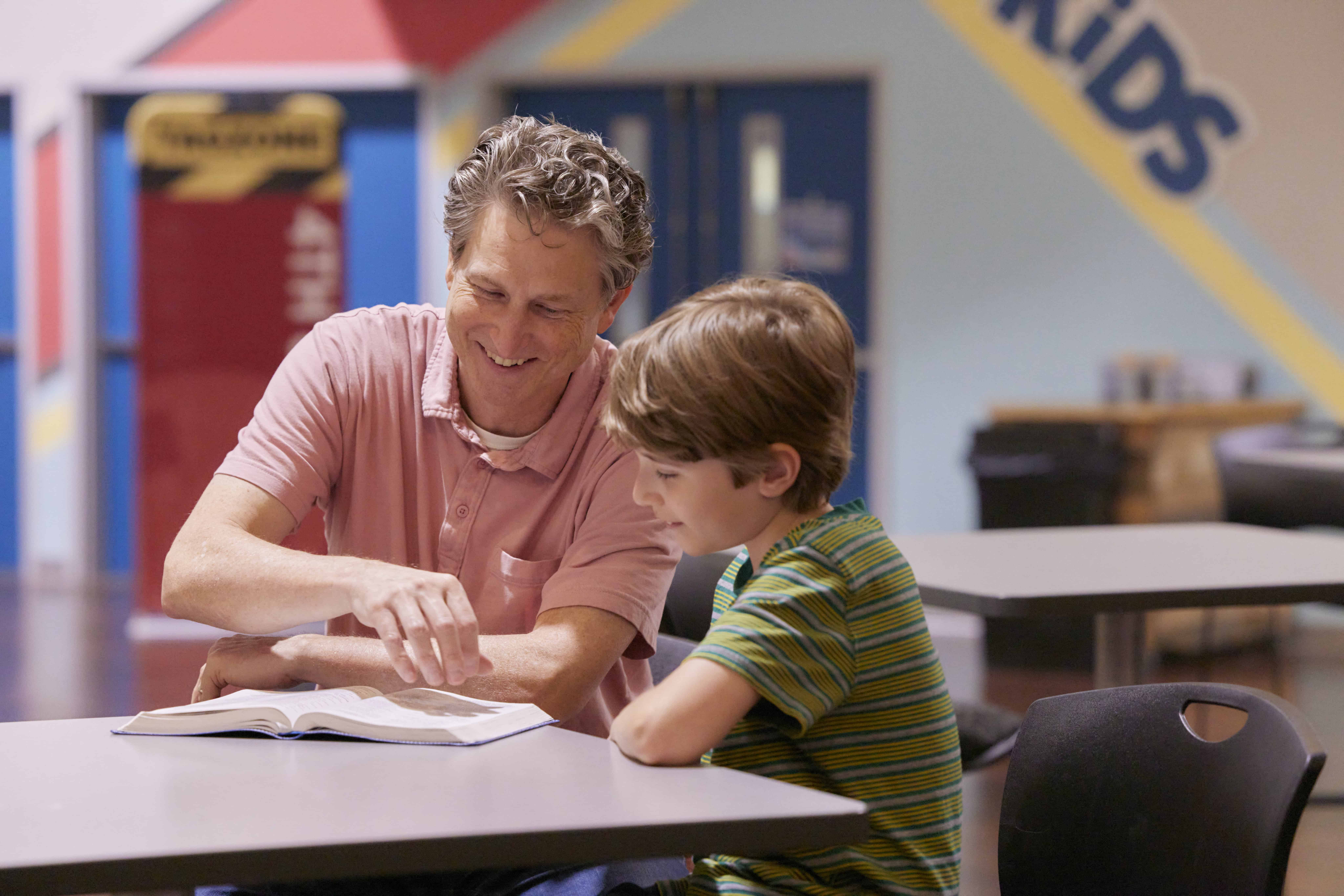 Volunteer reading Bible with a young boy at Rolling Hills Community Church.
