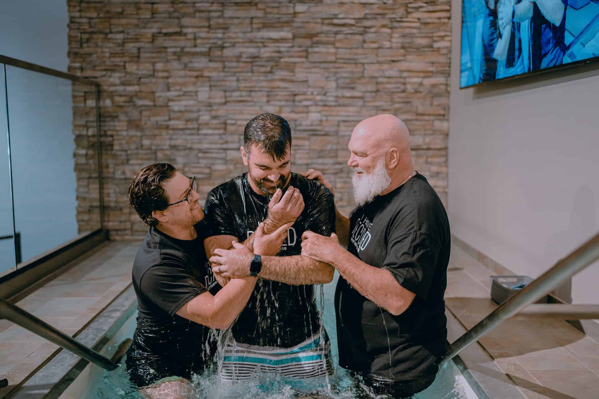 Baptism ceremony at Rolling Hills Community Church with three people in water, celebrating faith.