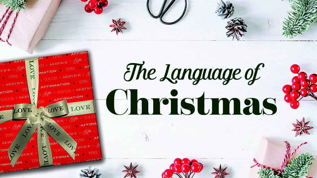 Christmas gift wrapped with "Love" ribbon, holiday decorations, pinecones, and festive accents.