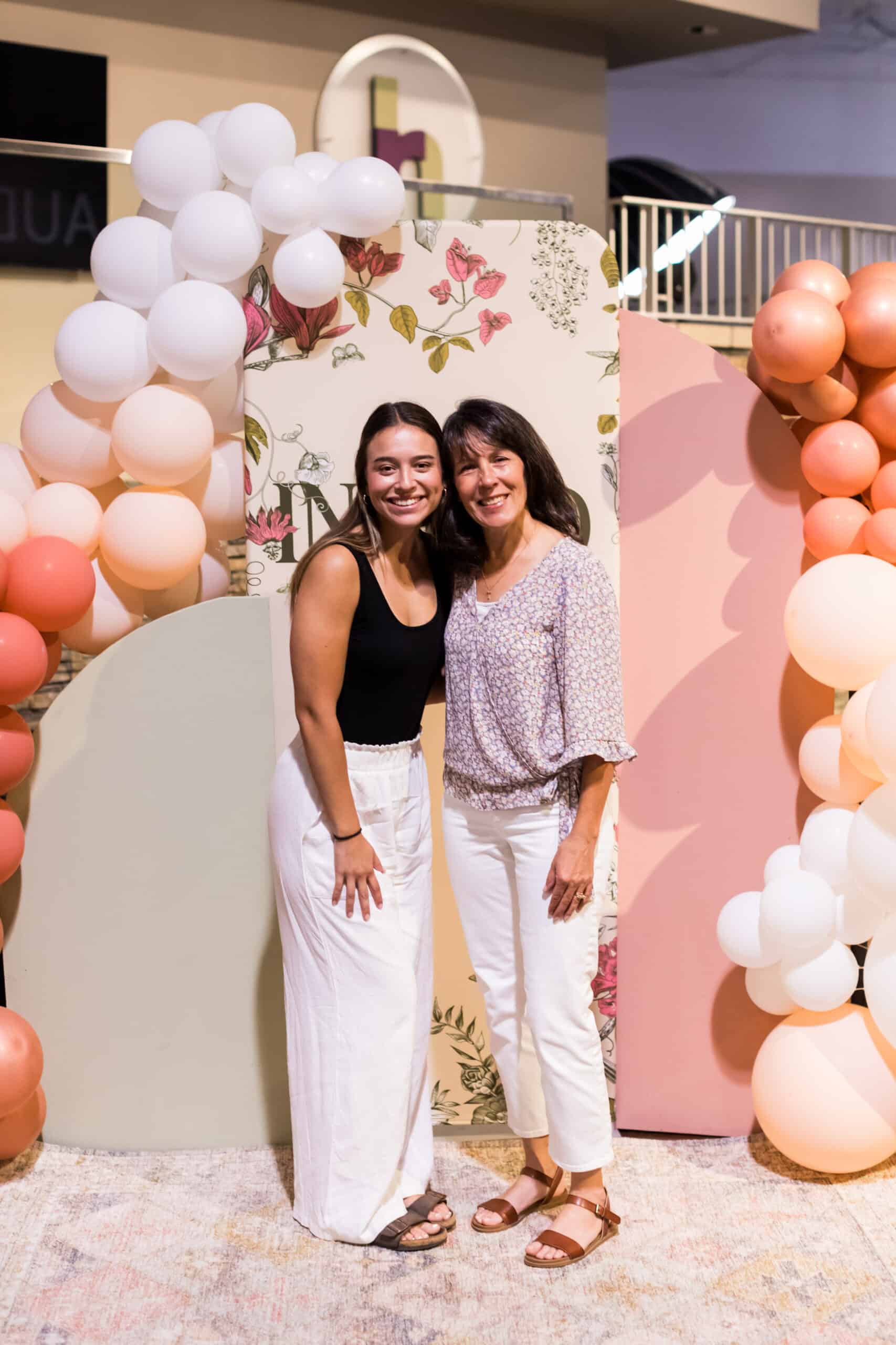 Two women smiling at a celebration event with balloon decorations at Rolling Hills Church.