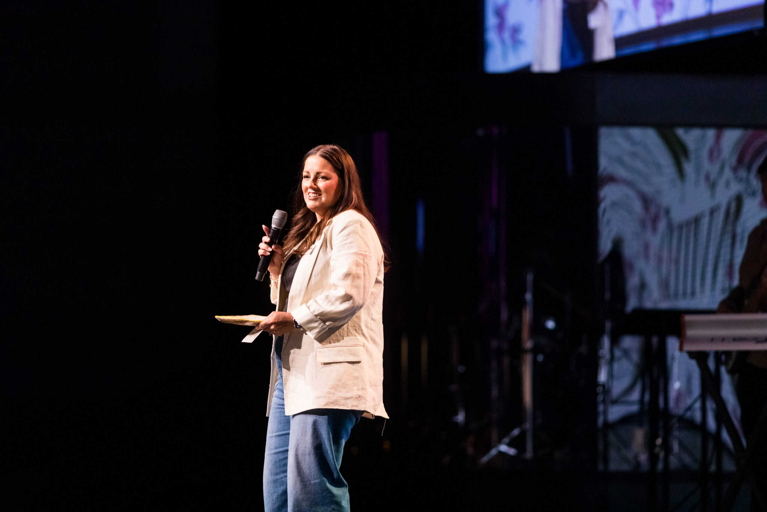 Woman speaking at Rolling Hills Community Church event with microphone and stage.