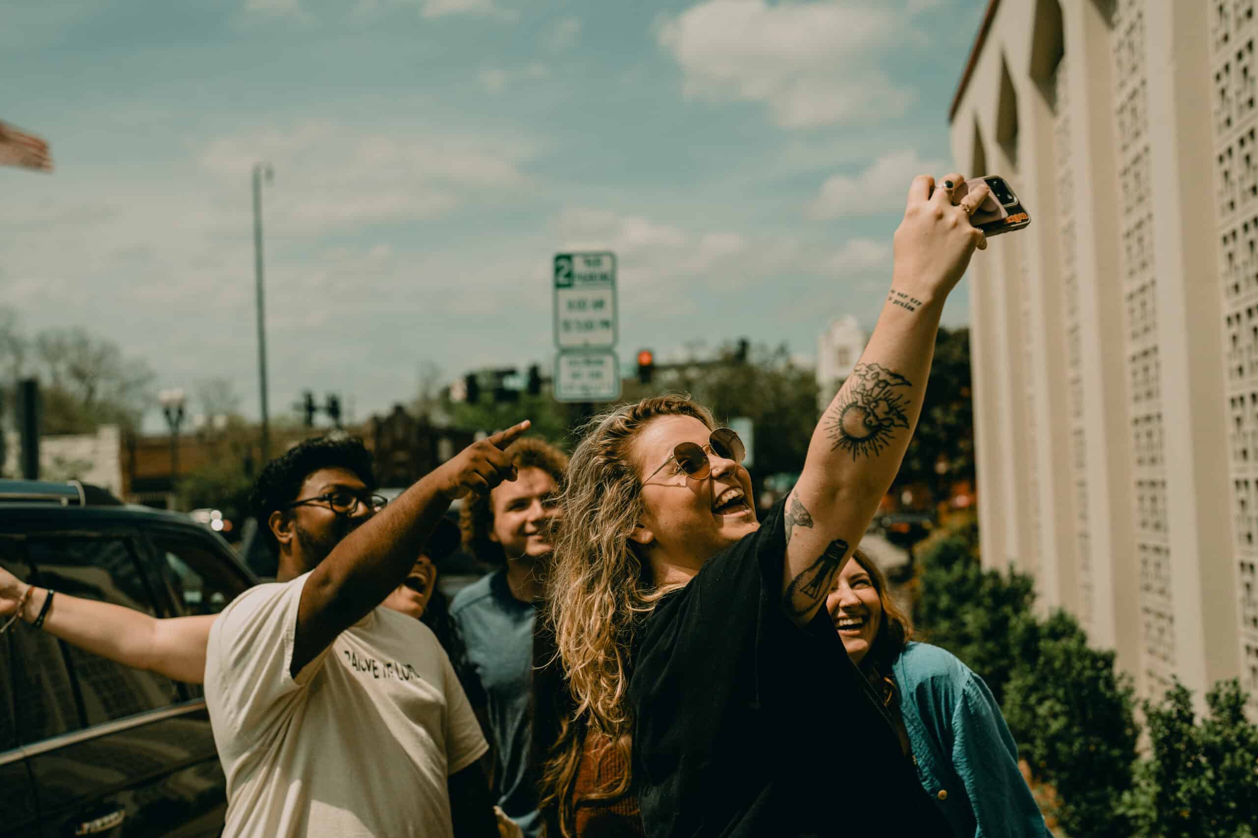 Group of diverse young adults taking a selfie outdoors in an urban setting.