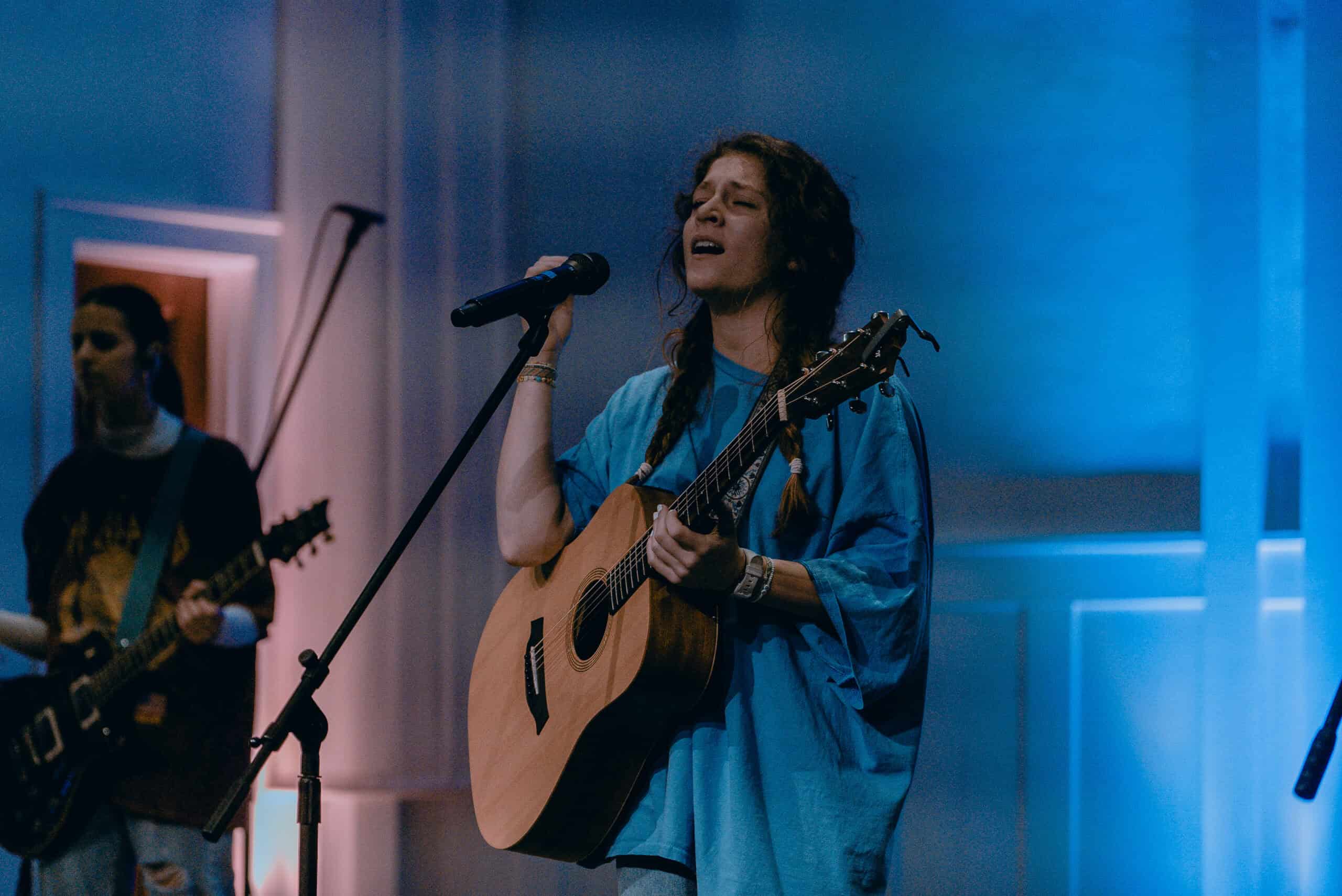 Woman singing and playing guitar during worship service at Rolling Hills Church.