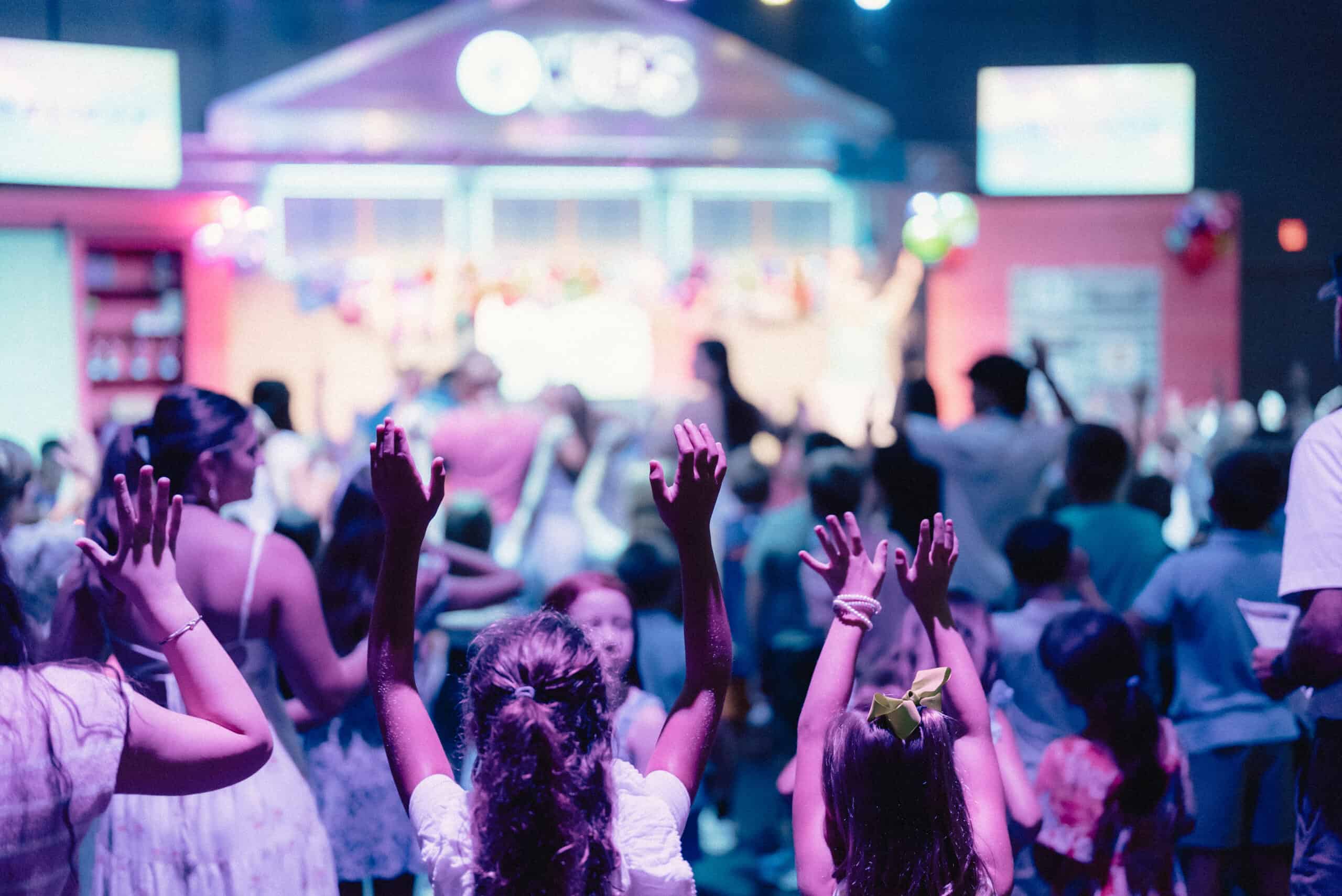 People raising hands during worship at Rolling Hills Community Church event.