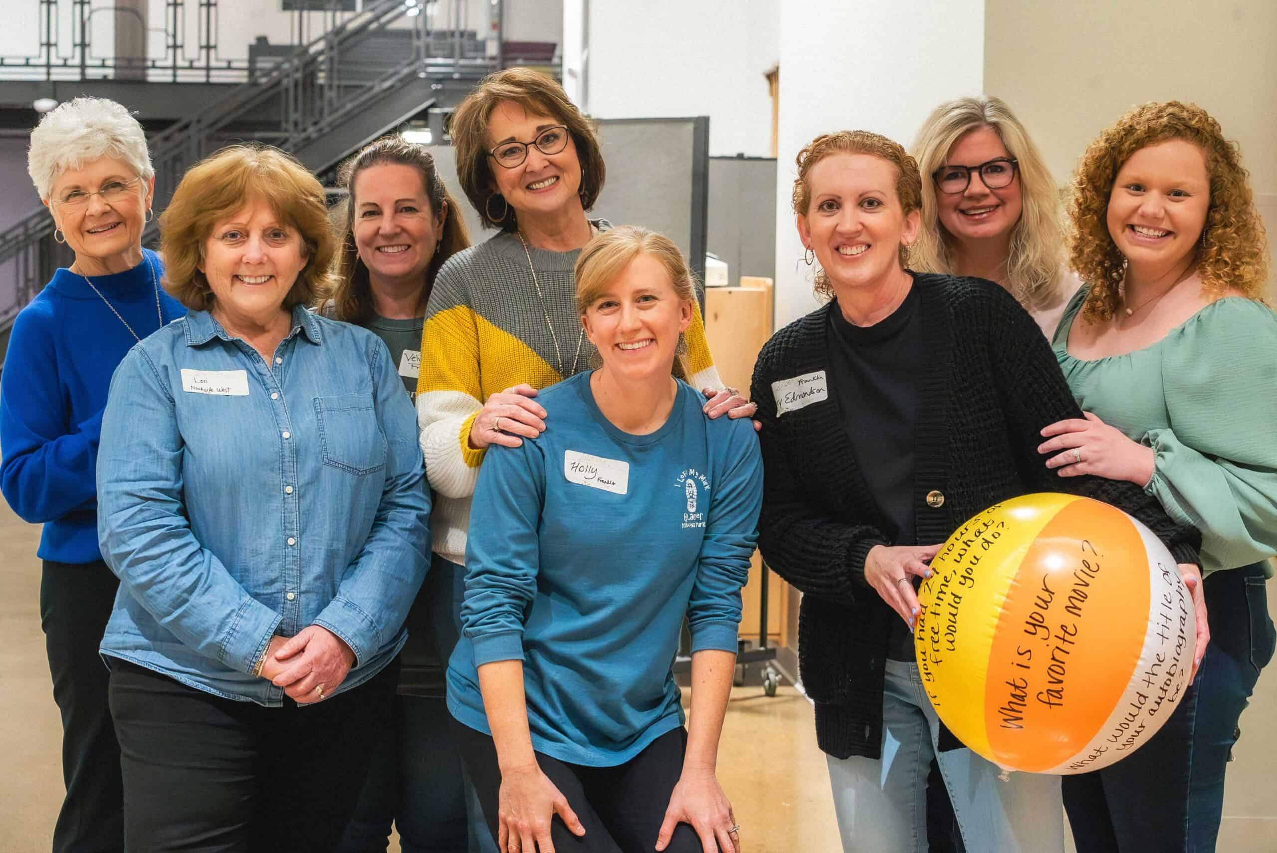 Community group at Rolling Hills Church with smiling women, holding a beach ball during church event.