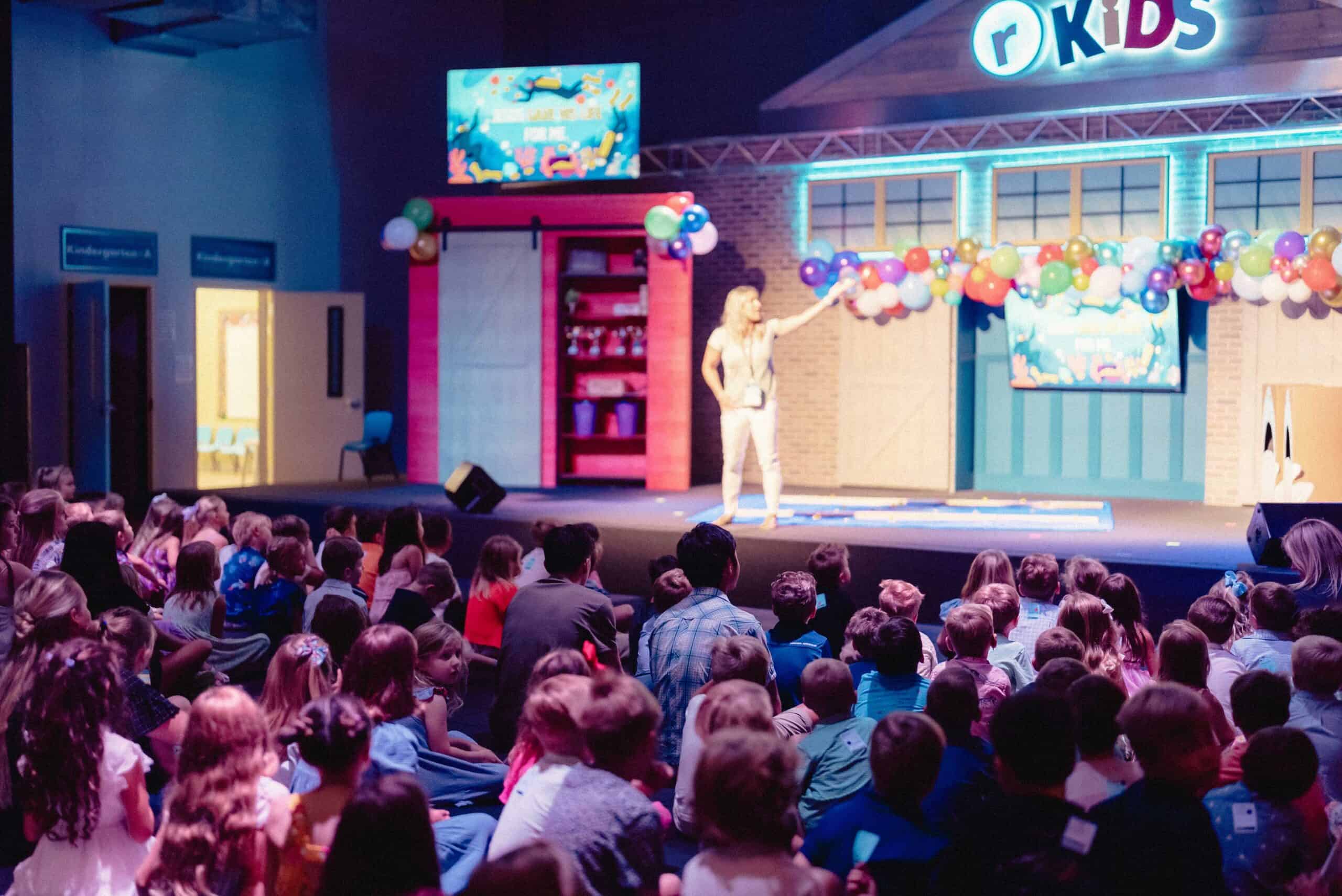 Kids event at Rolling Hills Community Church with stage, balloons, and audience.