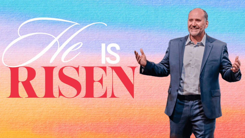 Man speaking at Easter service with "He Is Risen" background at Rolling Hills Community Church.