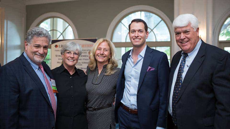 Group of five professionals at Romano Law Group event in a bright, elegant office setting.