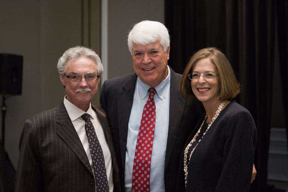 Group of three professionals at Romano Law Group event smiling for photo.