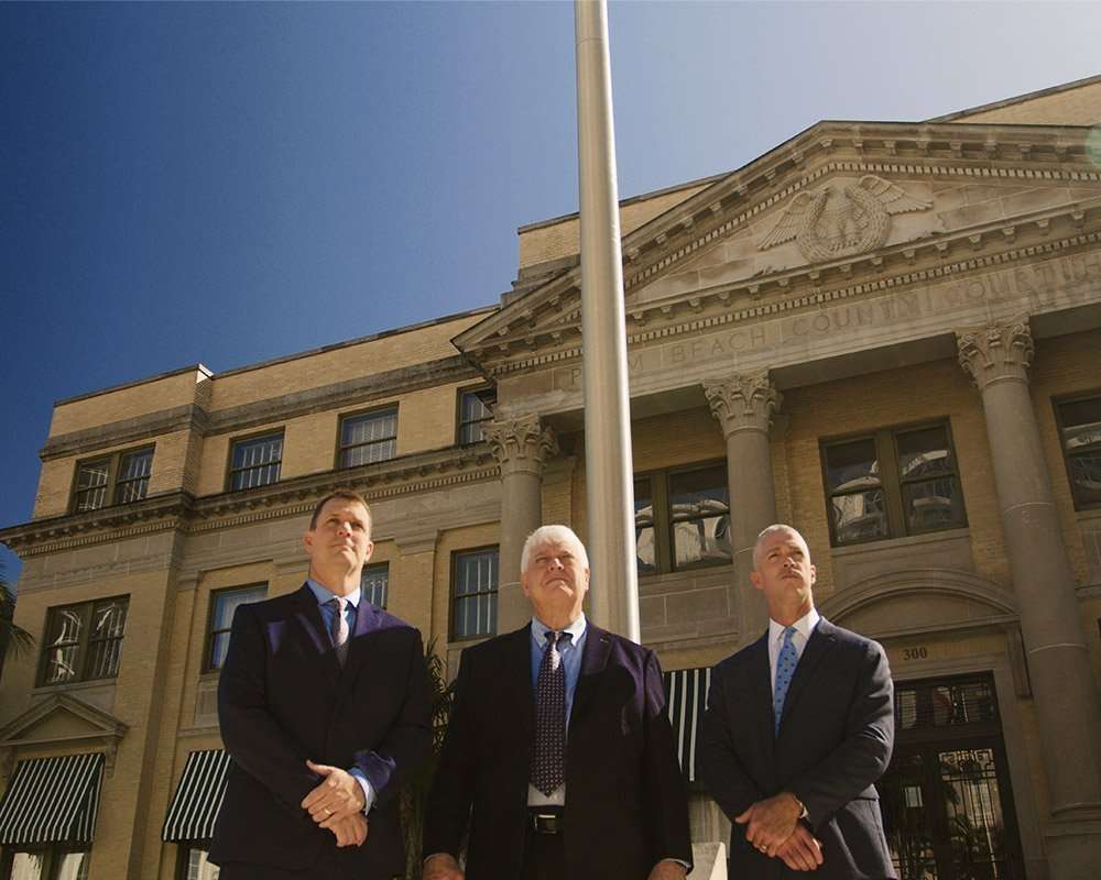 Eric, John and Todd Romano standing in front of a courthouse with a flagpole.