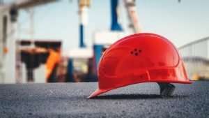 Red safety helmet on a construction site with cranes in background.