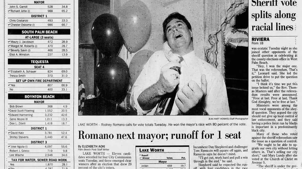 Black and white photo of a man speaking at a political event with balloons in the background.