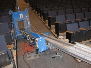 Theater seat removal machine in an auditorium with empty seats and a long track.