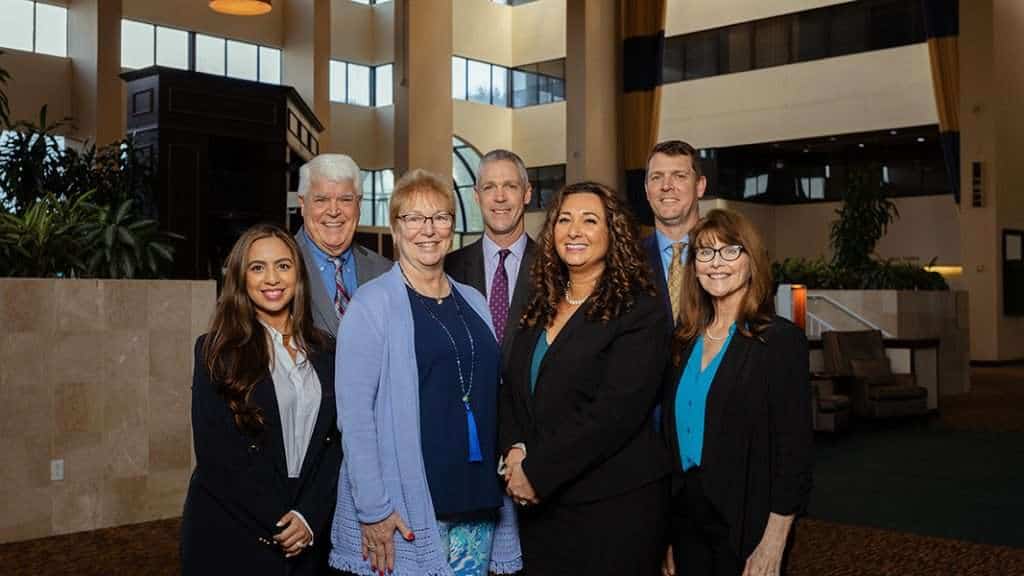 Group of professional lawyers at Romano Law Group in a modern office lobby.