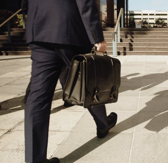 Businessman walking with briefcase outside office building.
