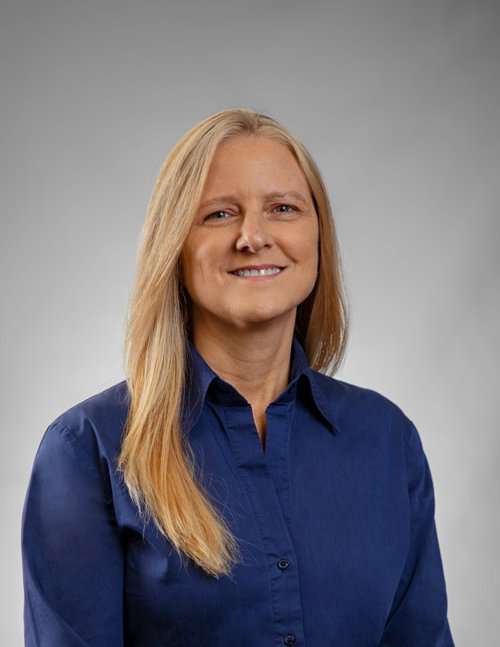 Professional woman in blue shirt smiling for Romano Law Group website.
