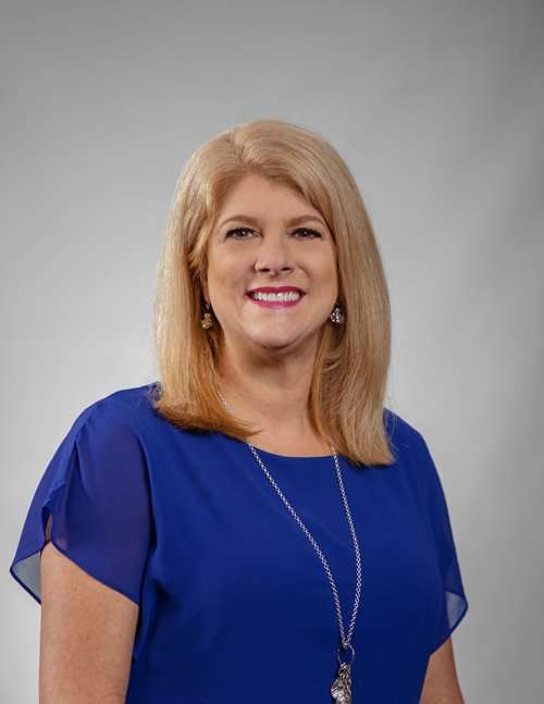 Professional portrait of a smiling woman in a blue dress for Romano Law Group.