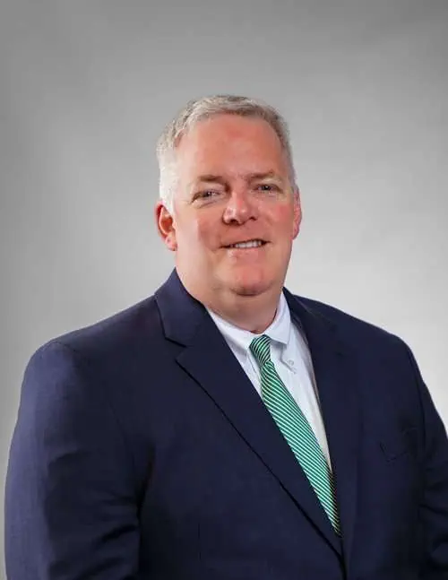 Professional portrait of a lawyer in a navy suit and green tie at Romano Law Group.