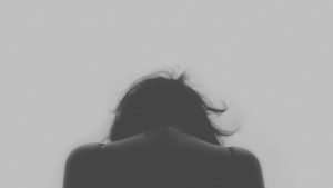 Person with head down, expressing stress or sadness, in black and white.