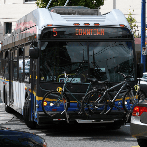 City bus with bike rack on front displaying route 5 to Downtown in urban setting.