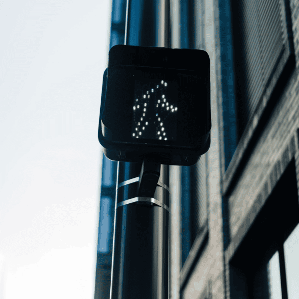 Pedestrian crossing signal on city street with building in background.