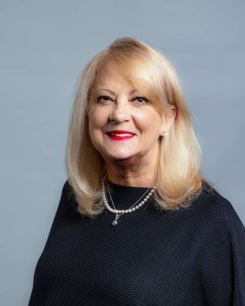Professional portrait of a smiling blonde woman in black attire for Romano Law Group.