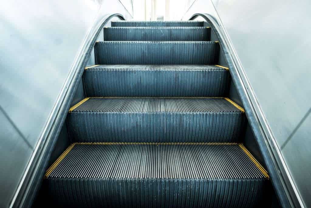 Empty escalator with metal steps and yellow safety lines at the edges.