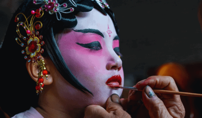 Young girl receiving face paint in preparation for the traditional Piaose parade in Taishan.