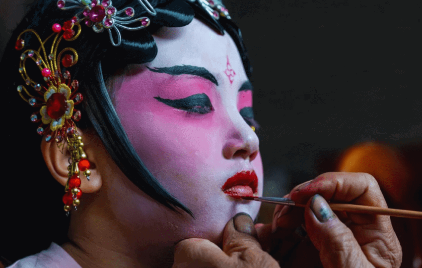 Young girl receiving face paint in preparation for the traditional Piaose parade in Taishan.