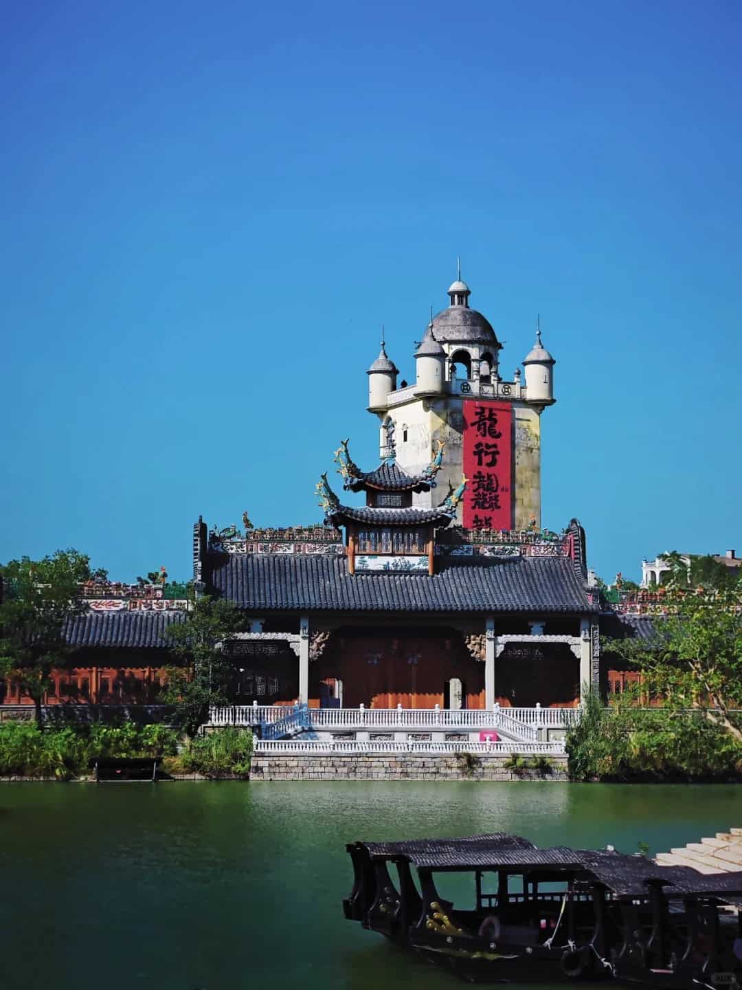 Kaiping Diaolou and traditional Chinese building by the river under a clear blue sky.