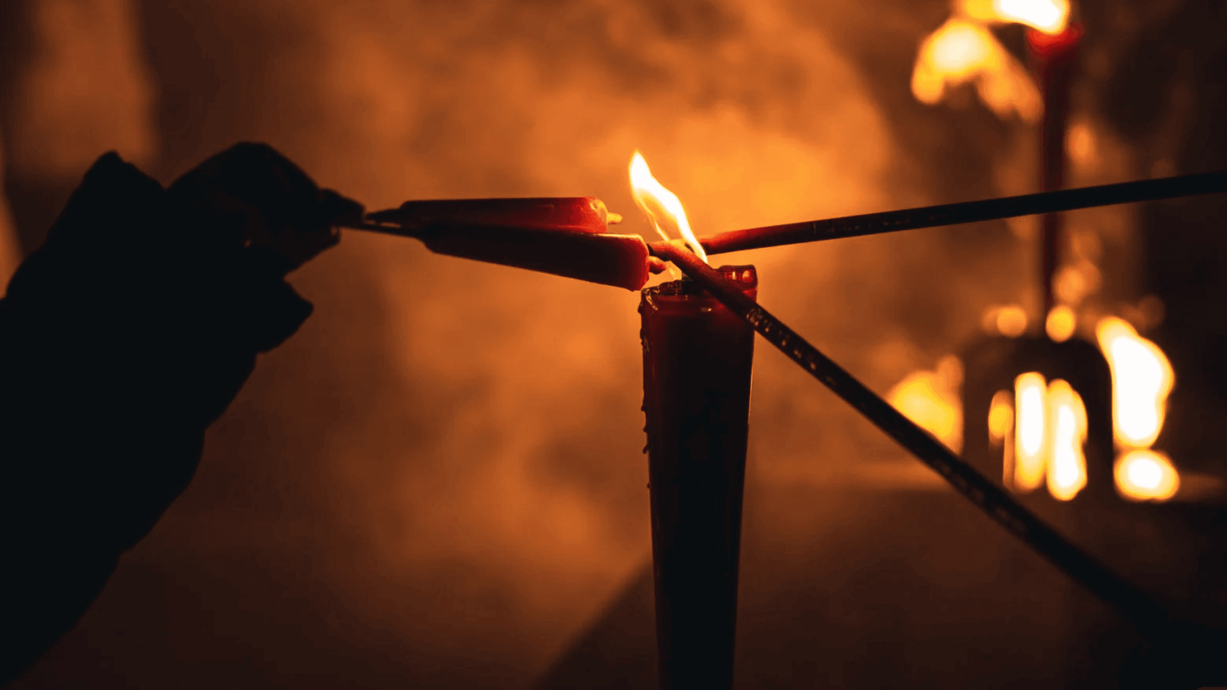 Lighting incense sticks from a candle flame during modern ancestor worship practices.