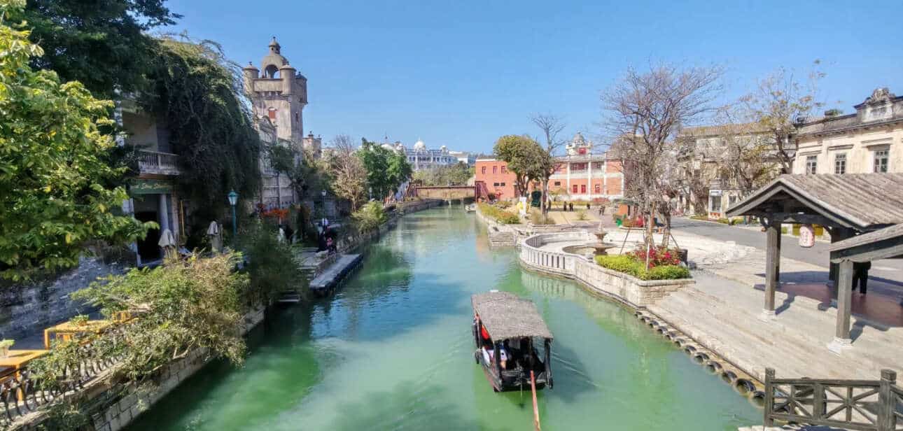 A scenic canal with traditional architecture, featuring a boat gliding through the water in an ancient town linked to the Guan clan.