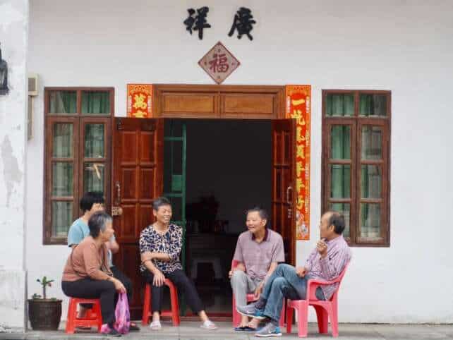 Elderly Taishanese people sitting outside a traditional home in Taishan, Guangdong, engaging in conversation.