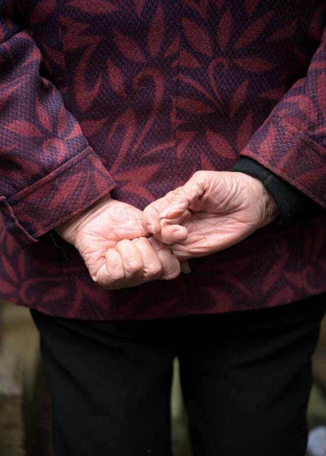 Close-up of an elderly person's hands clasped behind their back, symbolizing remembrance and legacy during Qingming.