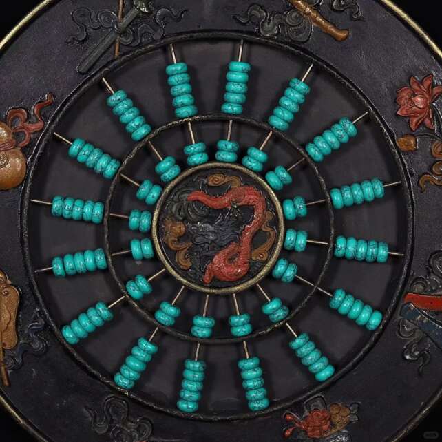 A circular ornamental abacus with turquoise beads and a central dragon design, framed by intricate carvings of mythical symbols, showcasing its dual role as a tool and artwork.