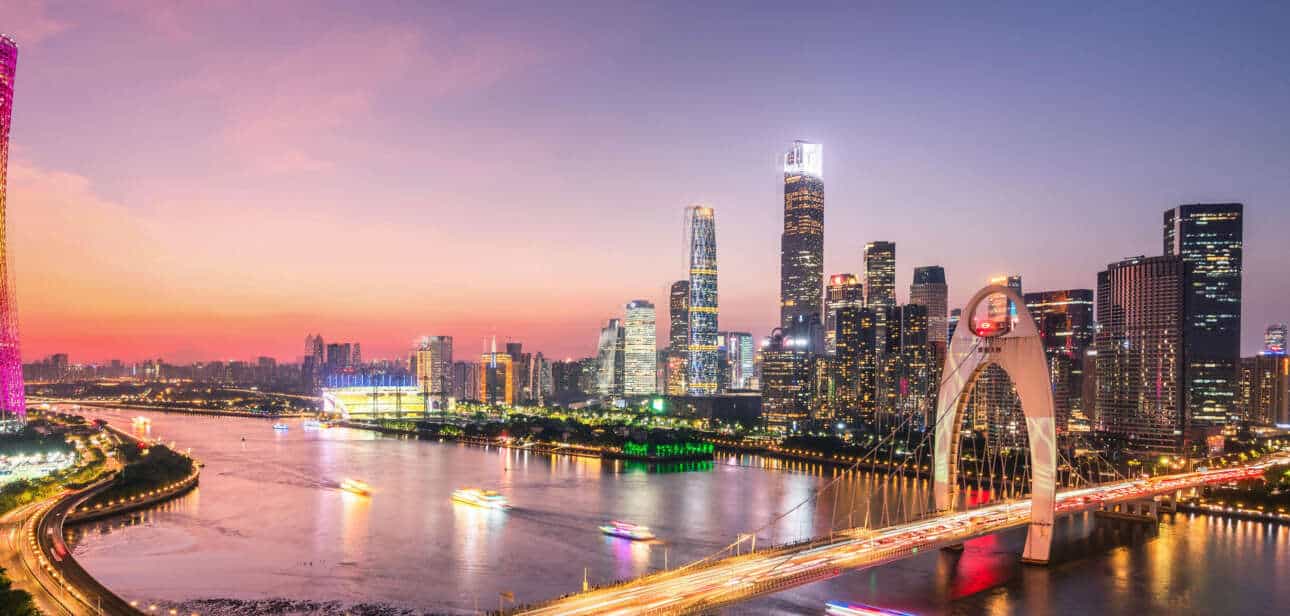 A vibrant sunset over Guangzhou’s skyline featuring the Canton Tower and modern skyscrapers, representing the economic growth of the Siyi Greater Bay Area Development.
