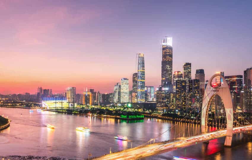 A vibrant sunset over Guangzhou’s skyline featuring the Canton Tower and modern skyscrapers, representing the economic growth of the Siyi Greater Bay Area Development.