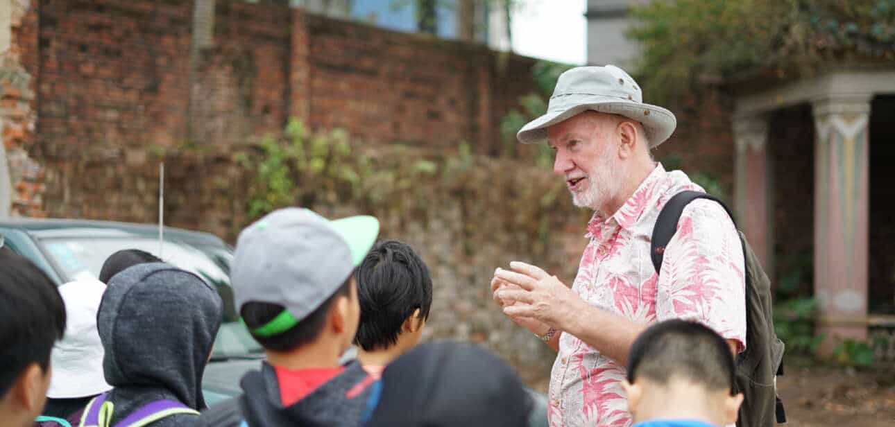 Peter Stuckey speaking to a group of students during a tour in Kaiping Tangkou, with traditional brick architecture in the background.