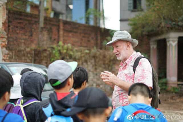 Peter Stuckey speaking to a group of students during a tour in Kaiping Tangkou, with traditional brick architecture in the background.