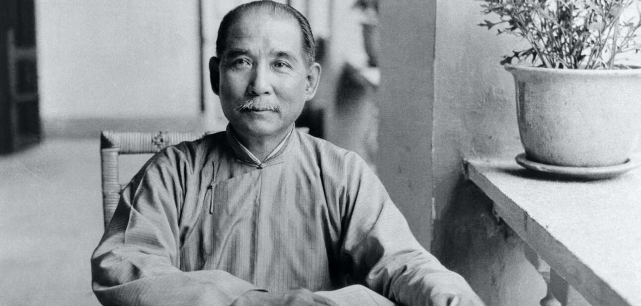 Historical photo of Sun Yat-Sen seated at a table reading in Guangzhou, showcasing his dedication to learning and revolutionary ideals.