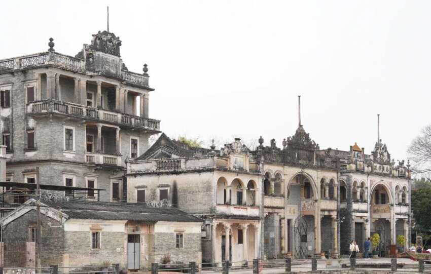 Cluster of Diaolou towers beside reflective water in rural China