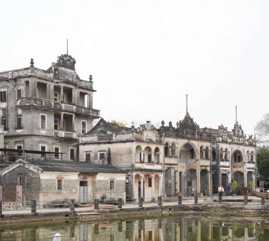 Cluster of Diaolou towers beside reflective water in rural China
